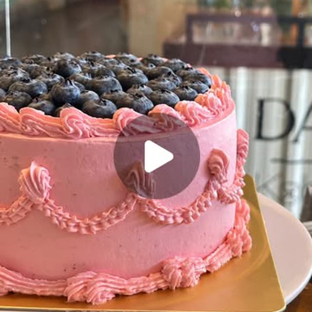 A pink buttercream cake crowned with fresh blueberries and finished with scalloped piping
