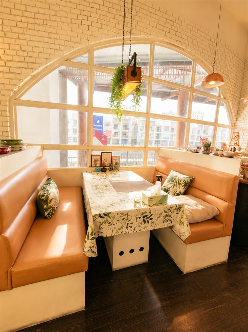 A cosy corner booth under a large arched window